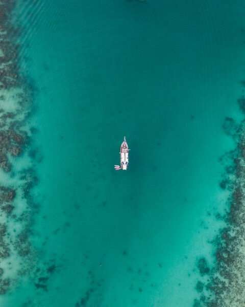 A boat on turquoise water seen from above