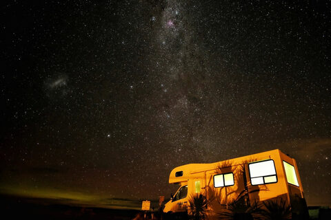 A camper lit up under the Milky Way