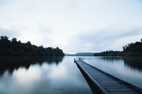 A dock reaching into a misty forest lake