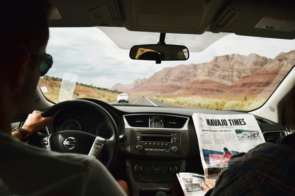 A driver at the wheel with paperwork on the dashboard