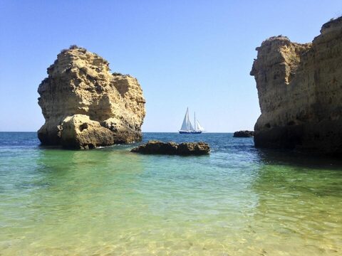 A sailboat anchored between rock formations in clear water