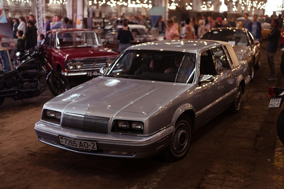 A silver car on a showroom floor beside other vehicles