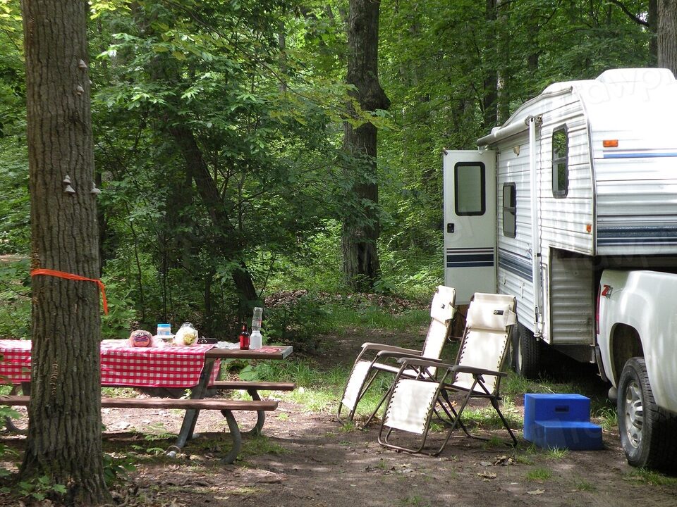A truck camper at a wooded campsite