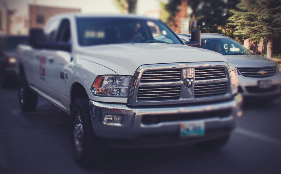 The front grille of a white pickup truck on a dealer lot