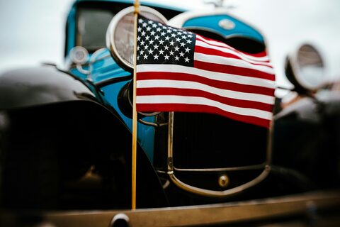 A classic car with a small American flag on the hood