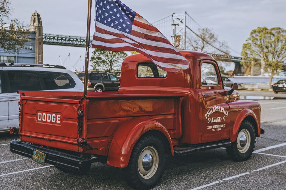 A restored red pickup truck flying an American flag