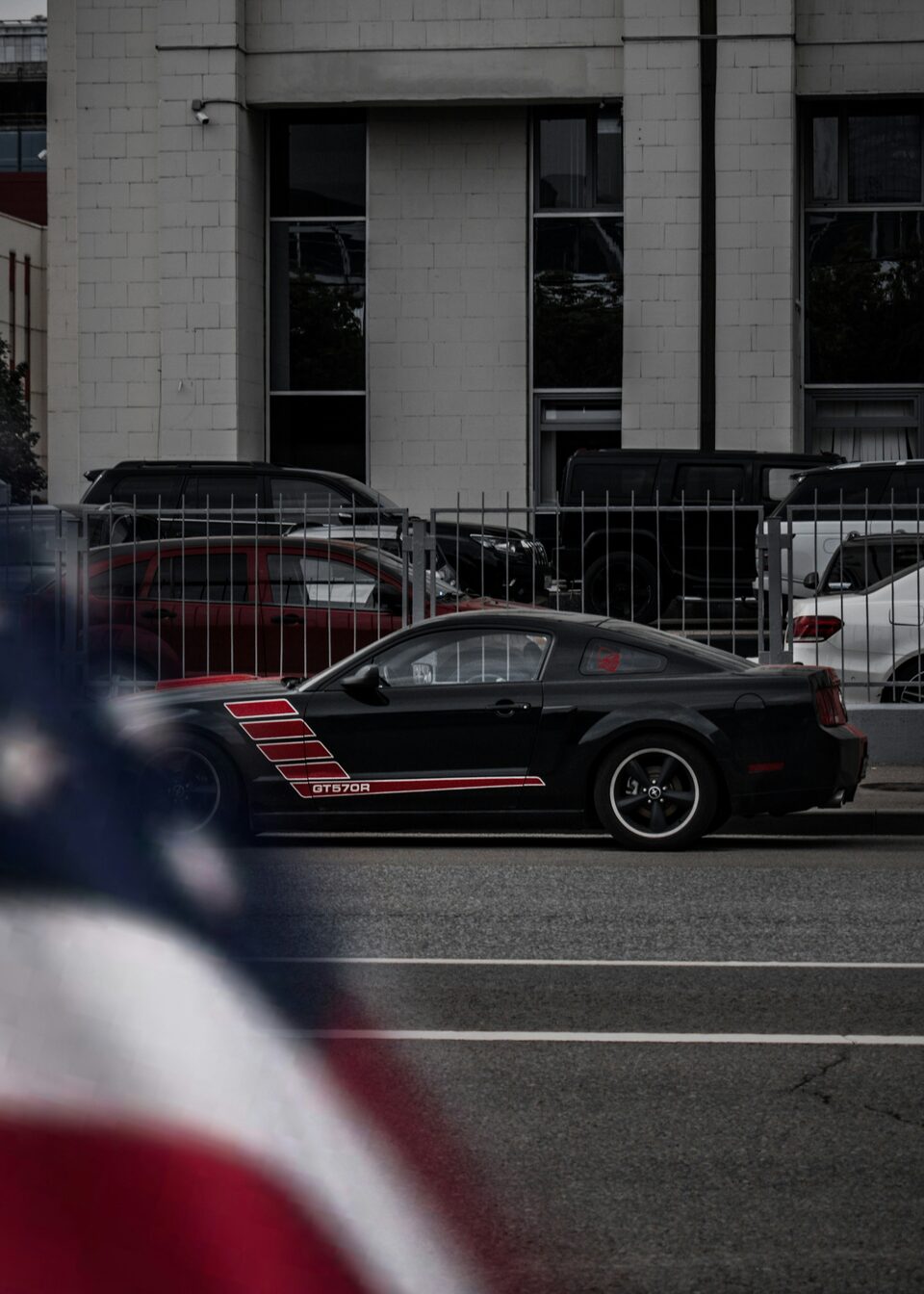 A black Ford Mustang with red stripes on a city street