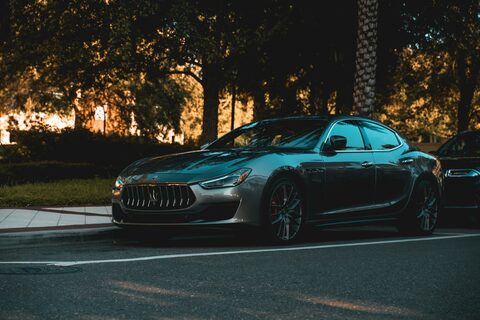 A dark sports coupe on a tree-lined road