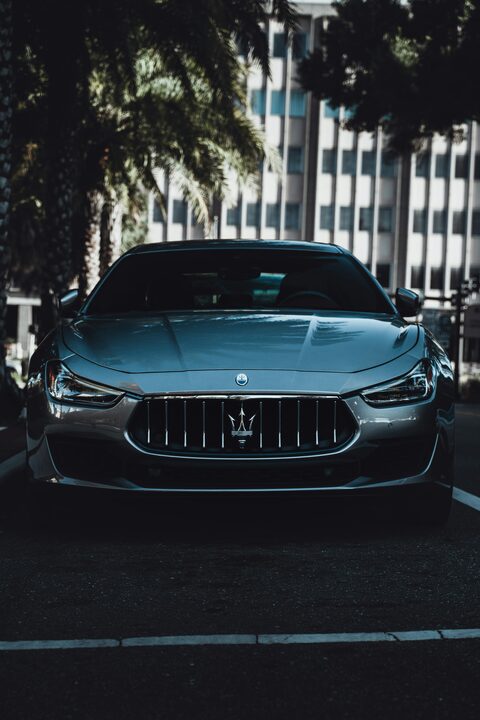 A dark luxury sedan photographed head on at dusk