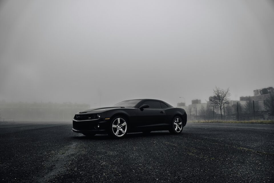 A black Chevrolet Camaro in the fog
