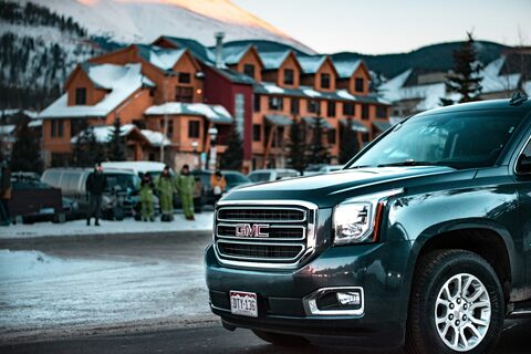 A black GMC SUV in a snowy resort town