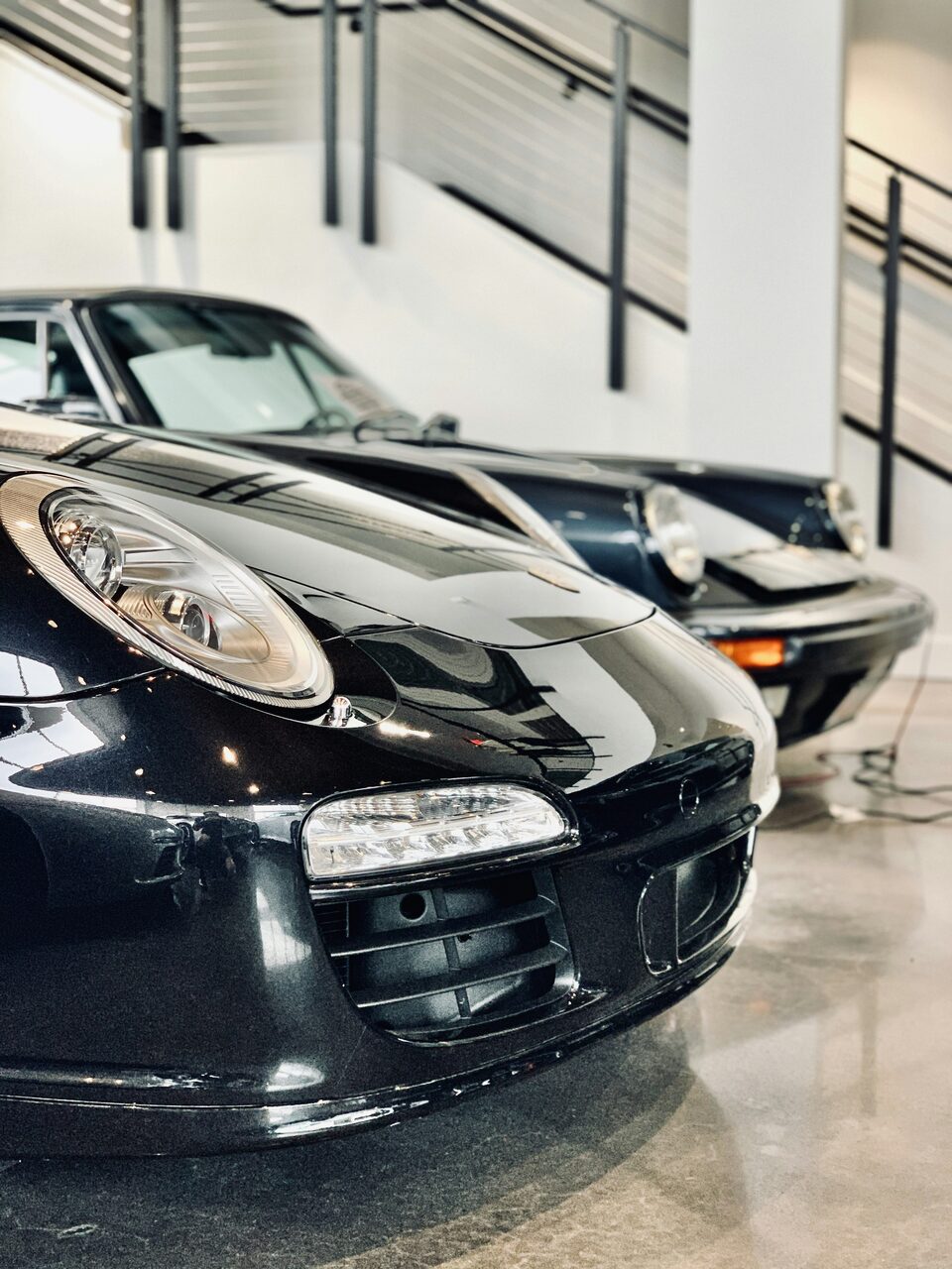 The headlight of a black Porsche up close