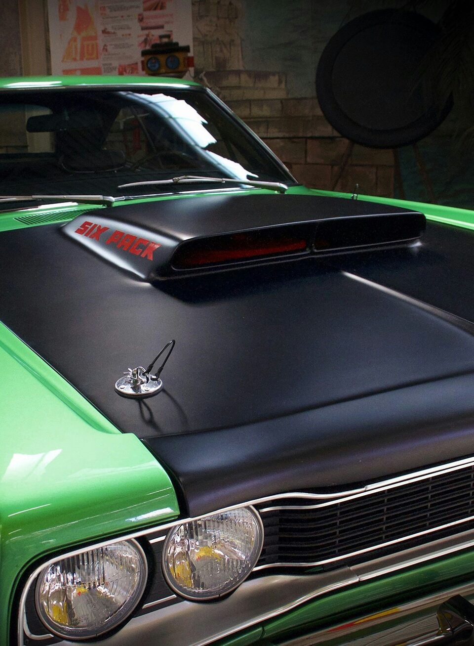 A green muscle car with a black hood scoop