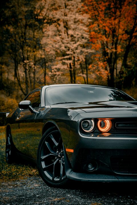 The glowing headlights of a dark Dodge Challenger