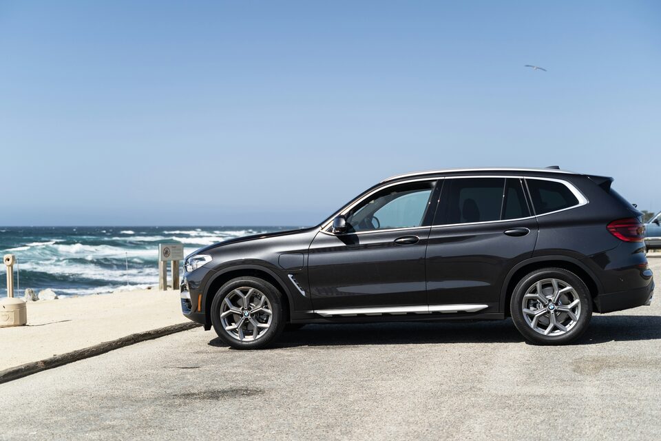 A black BMW SUV parked beside the ocean
