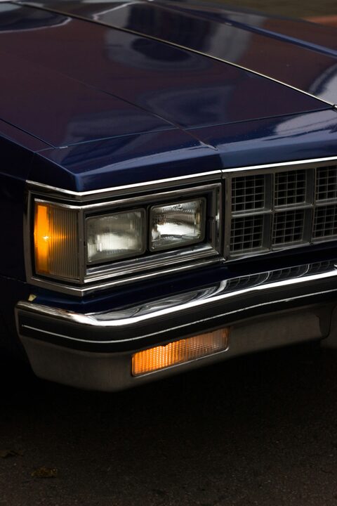The headlight of a navy classic Chevrolet
