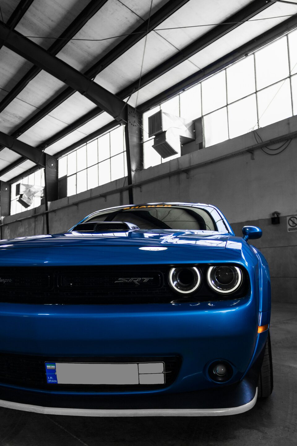 The glowing headlights of a blue Dodge Challenger