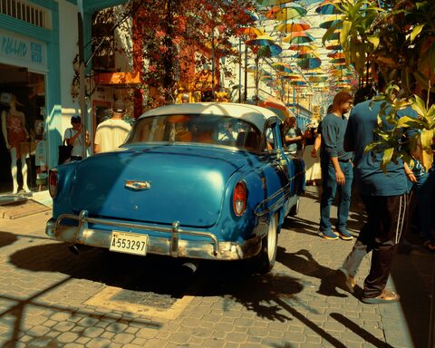 A teal classic Chevrolet on a busy festival street
