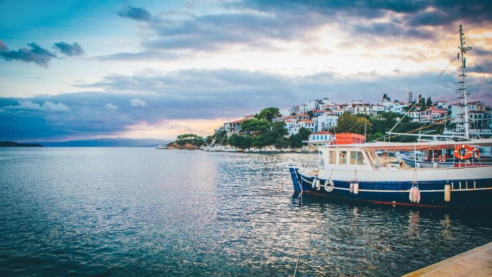 Boats moored in a harbor below a hillside town