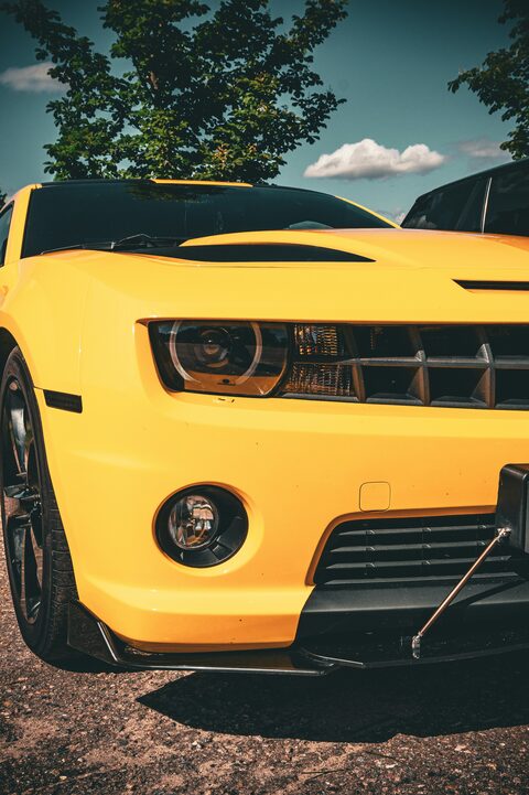 The headlight of a yellow Chevrolet Camaro