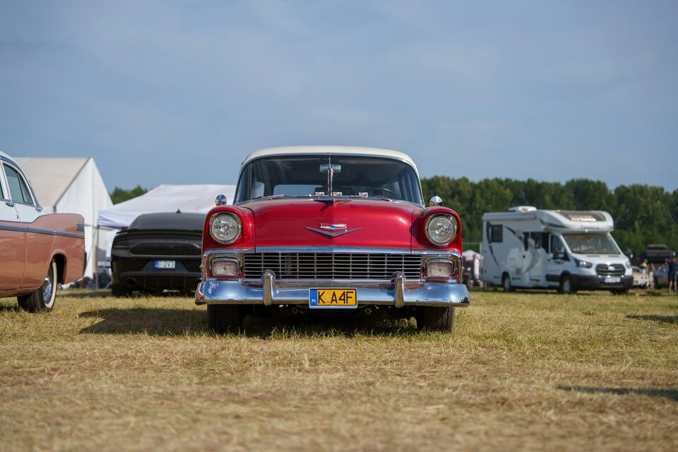 A red and white classic Chevrolet at an outdoor car show