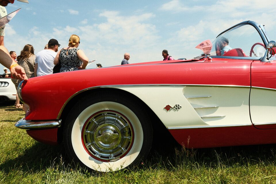 A red and white classic Corvette at an outdoor show