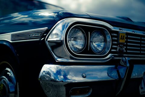 The twin headlights of a dark blue classic car