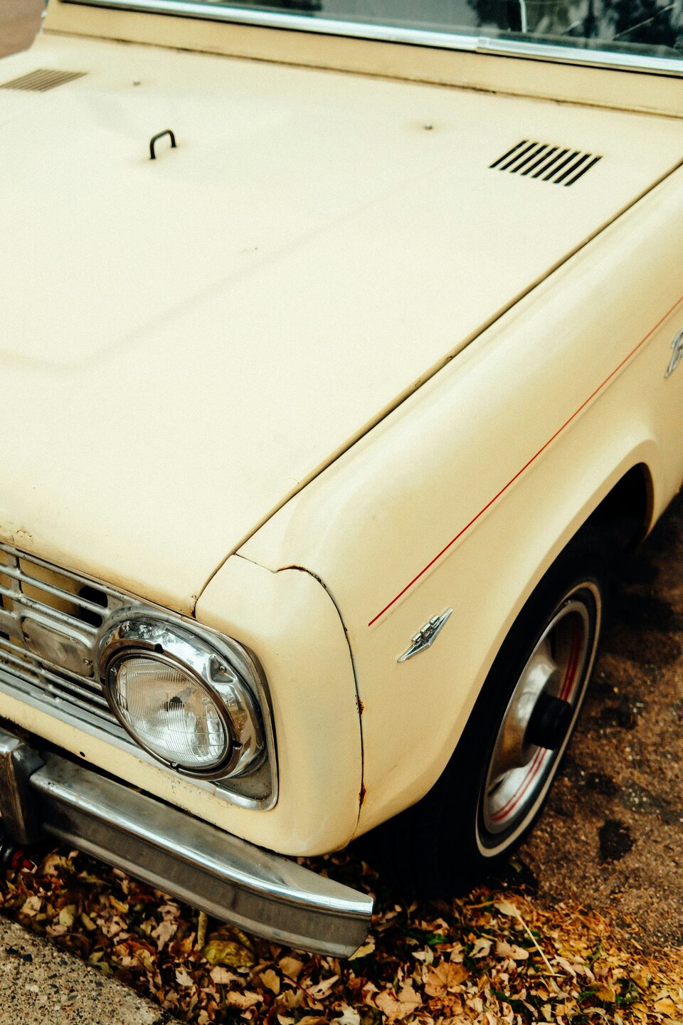 The cream front fender and headlight of a vintage car
