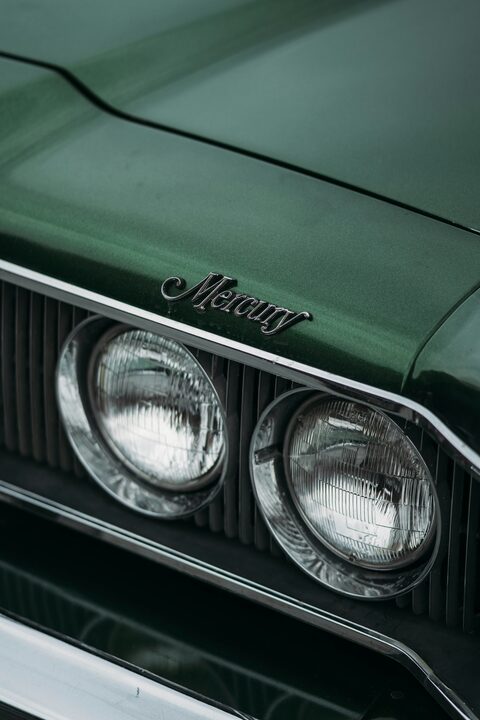 The twin headlights of a green classic Mercury