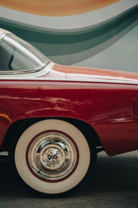 The whitewall tire and red fender of a classic car