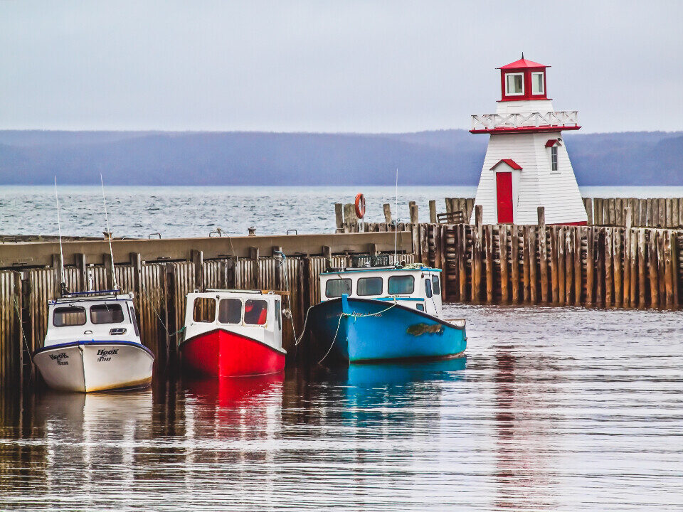 Colorful boats beside a red and white lighthouse
