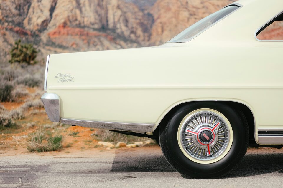 The rear wheel of a cream classic car in the desert