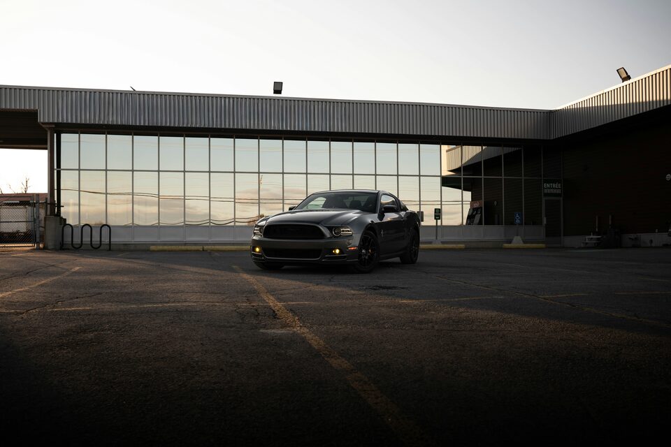 A dark sports car parked outside a modern glass building