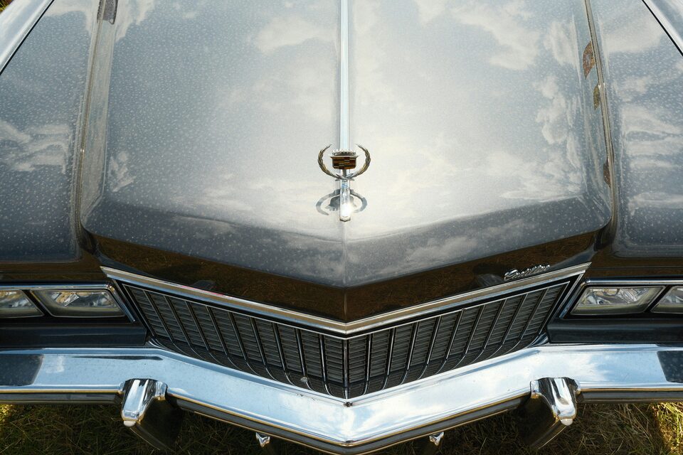 The hood and grille of a silver classic Cadillac
