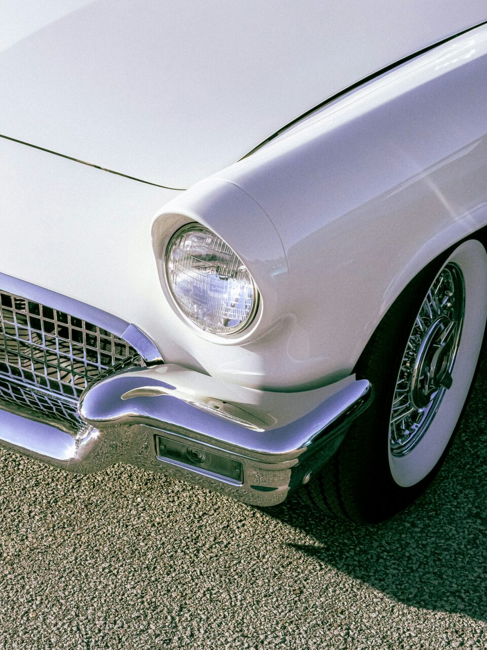 The chrome headlight of a white classic Corvette