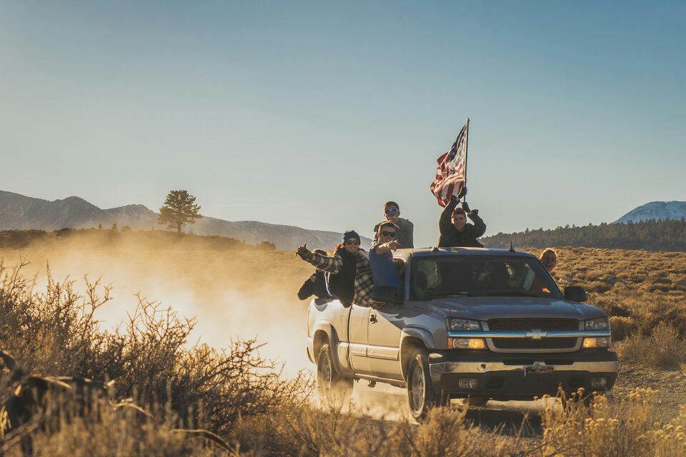 A pickup kicking up dust on a sunny country trail