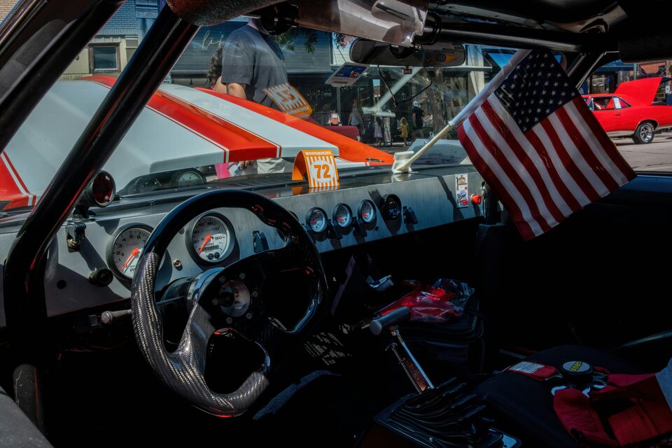 The interior of a classic car with a small American flag on the dash