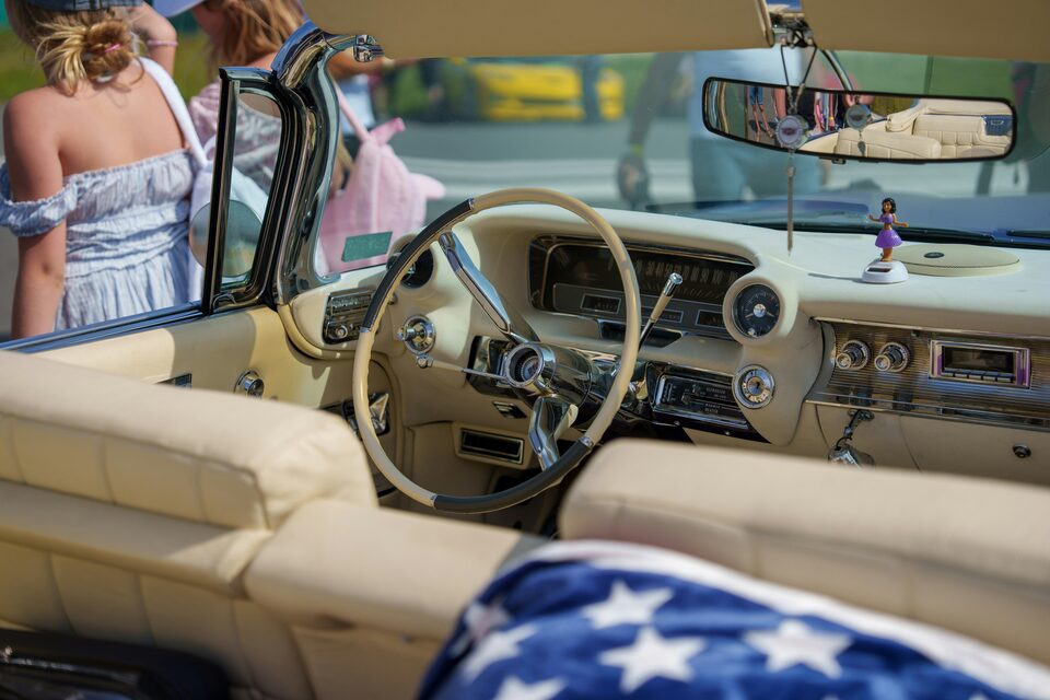 The cream interior of a classic convertible with a flag blanket