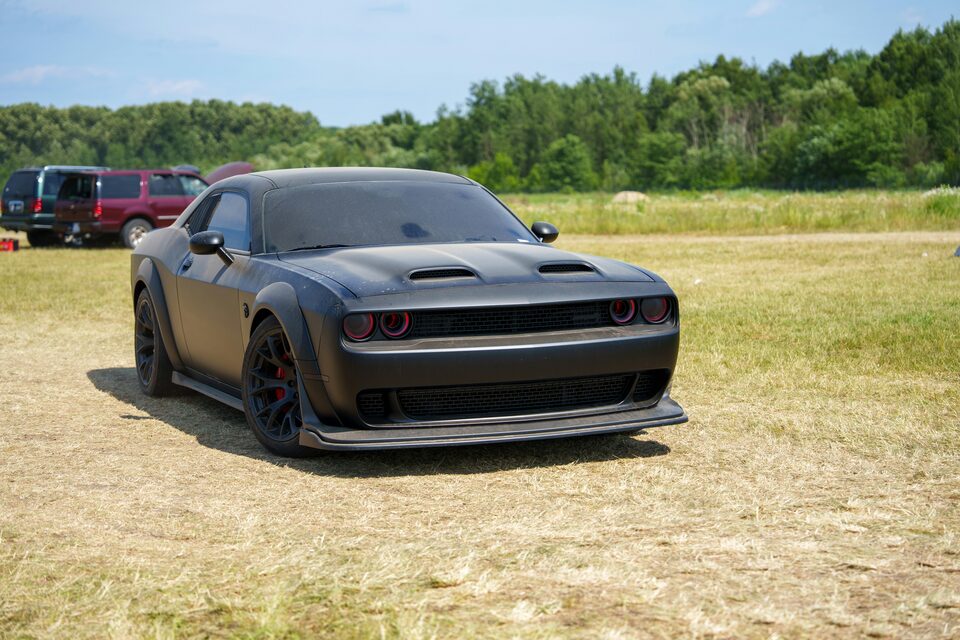 A dark gray Dodge Challenger on a grassy field