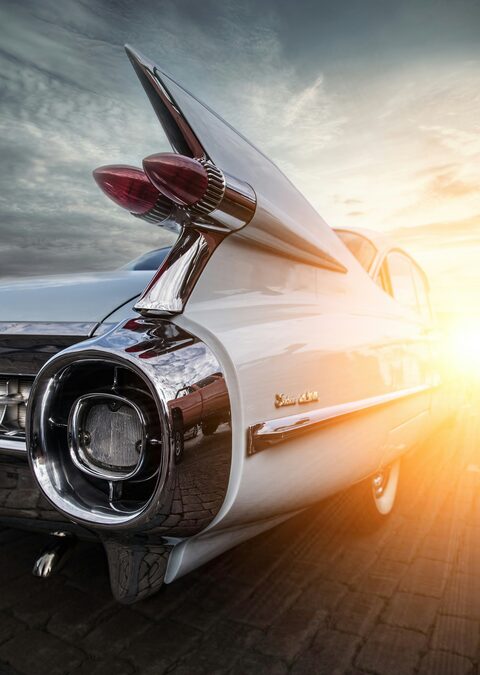 The tail fin and taillight of a classic Cadillac in the sun