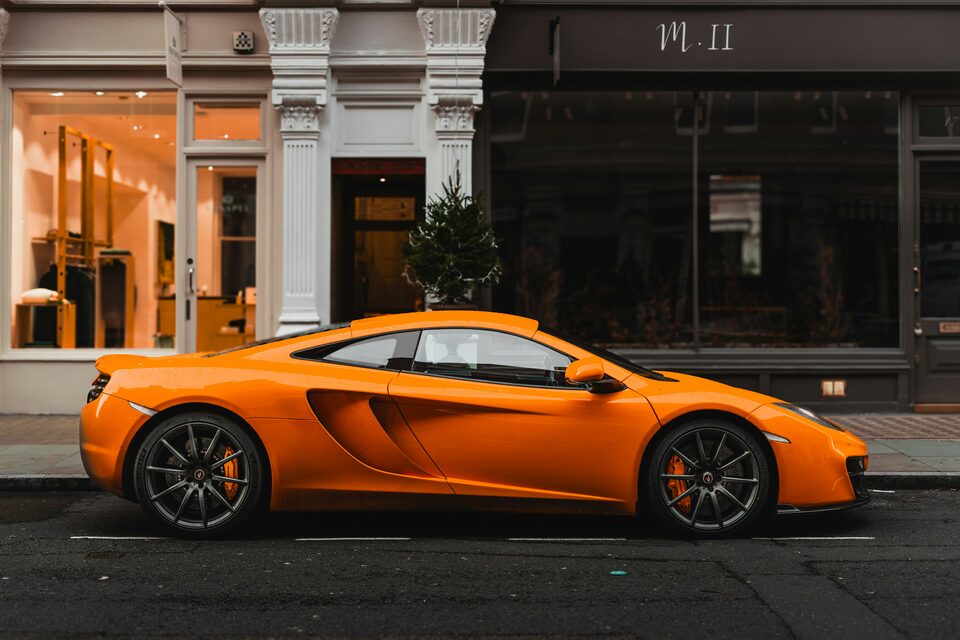 An orange McLaren parked outside a storefront