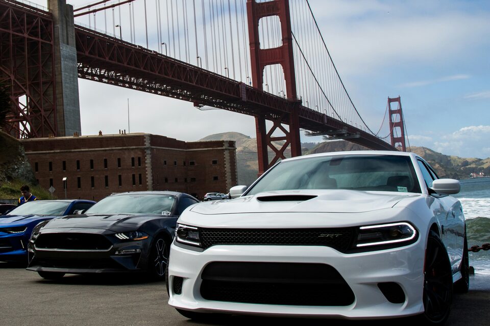 A white Dodge Charger parked below the Golden Gate Bridge