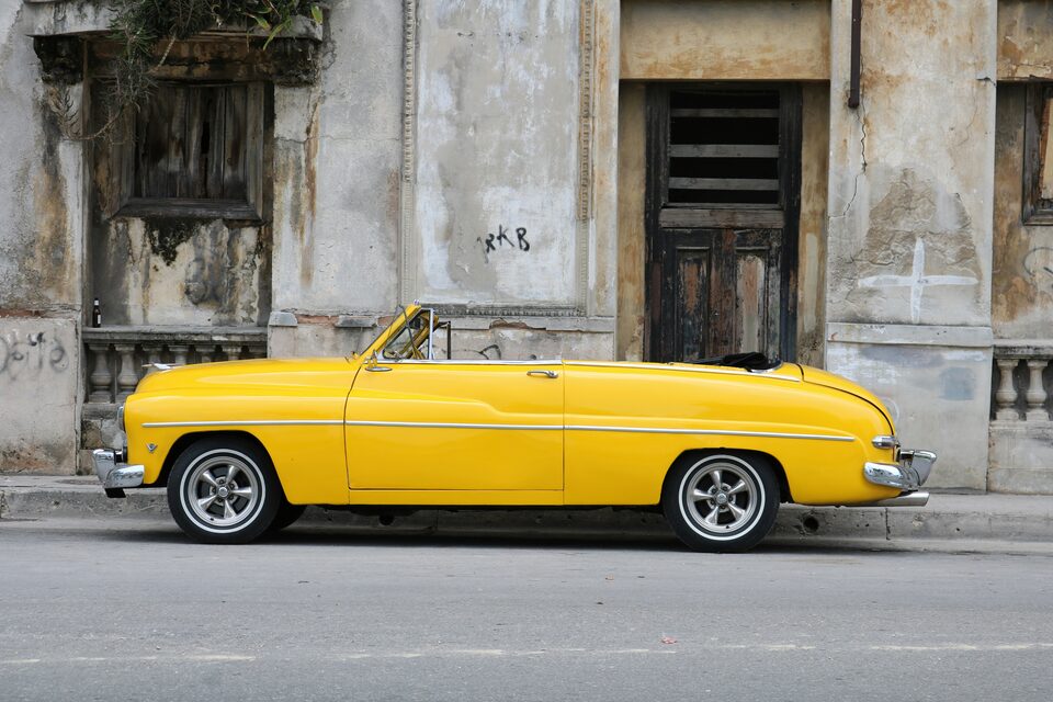 A yellow classic convertible parked on a city street