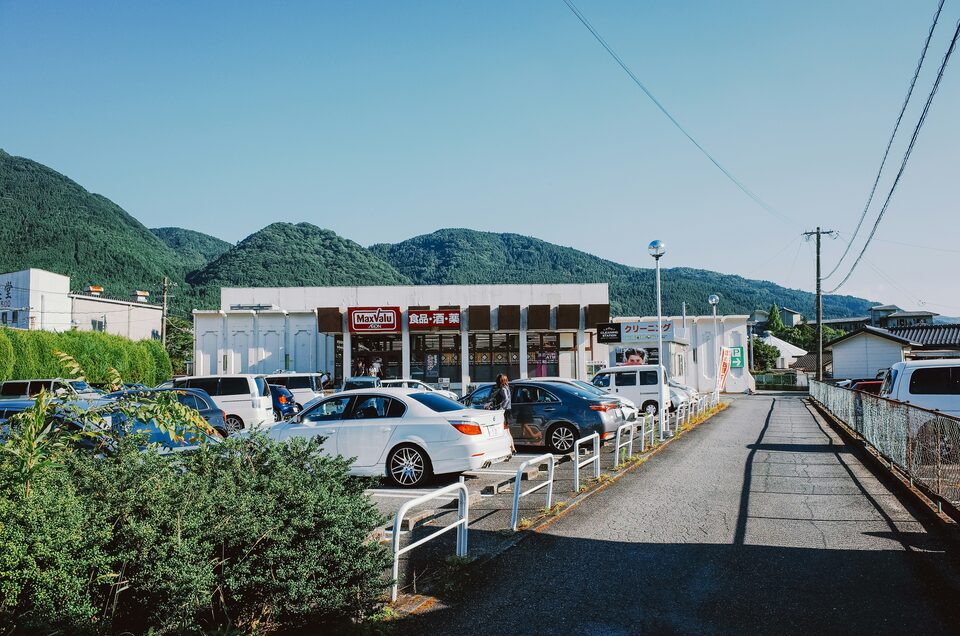 A dealer lot at the edge of town with hills behind it