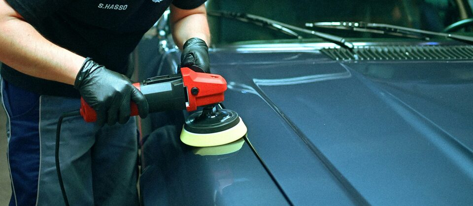 A detailer machine polishing a blue car