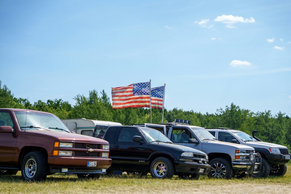 A row of pickup trucks on a dealer lot under American flags