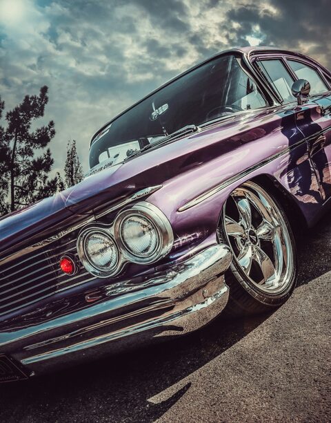 The twin headlights of a purple classic lowrider