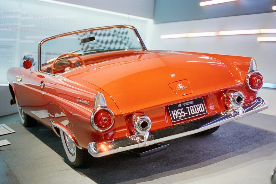 An orange classic Thunderbird convertible on a showroom floor