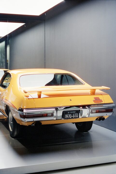 A yellow classic Pontiac GTO with a rear spoiler