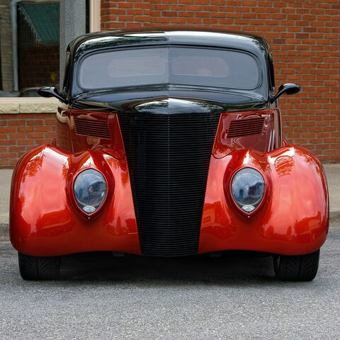 The rounded red front of a classic hot rod
